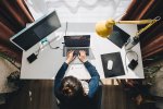 Frau sitzt im Homeoffice beim Schreibtisch und arbeitet am Laptop